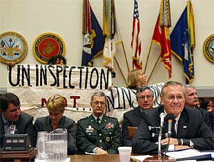 Varias personas protestan contra la política de Bush en Irak durante la comparecencia de Rumsfeld ante un comité. PLANO MEDIO - ESCENA