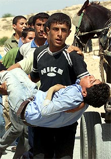 Un palestino transporta a un niño herido por las tropas israelíes ayer en Gaza.