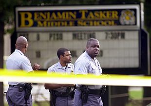 Tres policías patrullan frente al colegio donde el niño de 13 años fue alcanzado por un disparo.