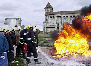 Un grupo de inspectores de armas de la ONU observa cómo dos soldados austriacos extinguen un fuego