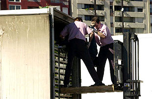 Dos personas sacan a uno de los cinco inmigrantes muertos en el interior de un camión en Algeciras.