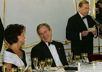 George Bush bromea con Jolanta Kwasniewski, la esposa del presidente polaco, mientras el presidente checo, Václav Havel, lee su discurso en la cena de gala.