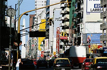 Entre el bullicio del tráfico de la célebre avenida de Corrientes destaca, al fondo, el Obelisco de Buenos Airesrn(67 metros de altura), uno de los símbolos de la ciudad, en el cruce con la avenida del Nueve de Julio.