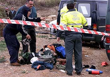 Uno de los trabajadores que viajaban en el autobús (izquierda) habla con agentes de la Guardia Civil.