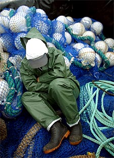 Un marinero descansa sobre unas redes de los trabajos de recogida del fuel del    Prestige. 