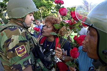 Una partidaria de Chávez regala rosas a un soldado.