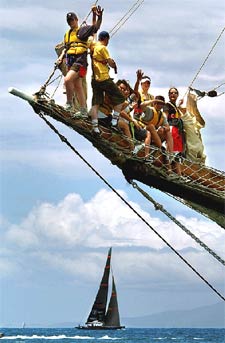 Un grupo de espectadores observa desde un barco el paso del velero  OneWorld. 