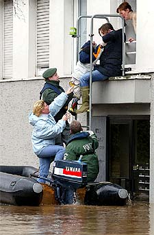Policías ayudan a un niño alemán a entrar en su casa con el portal inundado.