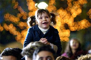 Una niña, llevada en hombros, mira y sonríe durante el espectáculo del desfile de los Reyes Magos, ayer en Barcelona.