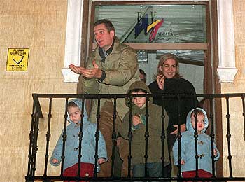 Iñaki Urdangarín pide caramelos a los Reyes Magos desde un balcón de Alcalá de Henares, acompañado de la Infanta Cristina y dos de sus hijos.