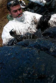 Un soldado limpia con una espátula las rocas de Nemiña (A Coruña).