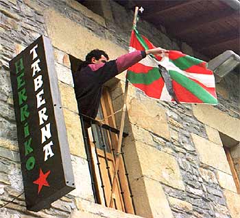 Un simpatizante de HB coloca una  ikurriña  en la  herriko taberna  de Mallabia tras la muerte de un etarra en 1997.