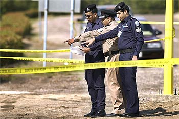 Policías kuwaitíes investigan en el área donde los dos norteamericanos fueron tiroteados cerca de Camp Doha.