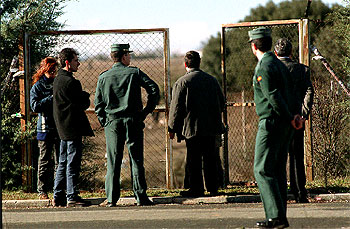 Guardias civiles y otros funcionarios en la verja de la fosa séptica donde fueron hallados los restos.