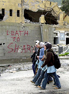 Varias jóvenes palestinas pasan junto a un cartel que dice 