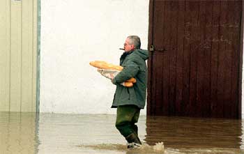 Un vecino de Astegieta (Álava) cruza una calle anegada con unas barras de pan.