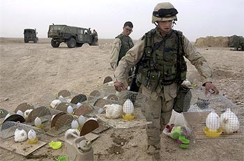 Un   marine   porta varias jaulas de pollos que se utilizan como alerta en caso de ataque químico.
