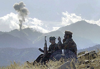Dos   muyahidin   charlan mientras observan el humo de las bombas lanzadas contra Tora Bora, en la pasada guerra afgana.