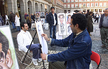Sadik Shahood dibuja una caricatura en la plaza Mayor. De pie, observándole, su hermano Ghalib.