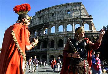 Dos hombres vestidos al estilo de los soldados romanos, ante el Coliseo.