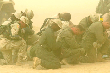 Soldados estadounidenses desplegados en la frontera entre Kuwait e Irak rezan en medio de una tormenta de arena.