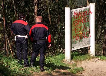 Dos  ertzainas  observan las amenazas contra Ibarrola en el bosque de Oma.