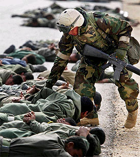 Un  marine  del Ejército de EE UU registra a un grupo de prisioneros iraquíes.