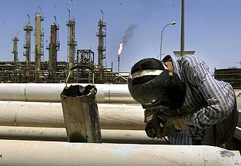 Un operario repara las conducciones de petróleo en una refinería de Bagdad.