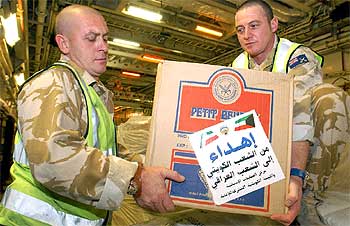 Dos  marines  transportan una caja con ayuda humanitaria para Irak ayer en la base británica de Sir Galahad.
