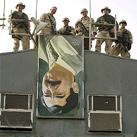 Miembros de la Guardia Costera de EE UU, sobre un retrato de Sadam Husein en Mina al Bakr.