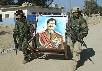 Soldados de la 101ª División Aerotransportada de EE UU trasladan un retrato de Sadam Husein en Nayaf.