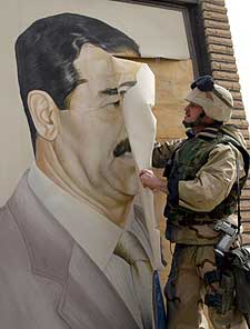 Un   marine   estadounidense arranca un retrato de Sadam, en la ciudad iraquí de Safwan.