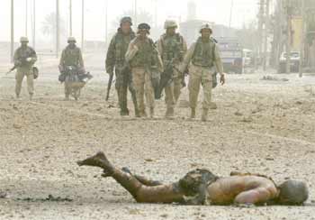 Soldados del Cuarto Regimiento del Tercer Batallón de EE UU pasan junto al cadáver de un iraquí ayer tras tomar un puente que conduce al centro de Bagdad.
