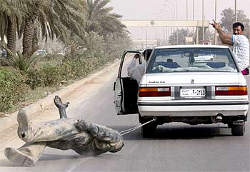 Dos iraquíes arrastran una estatua de Sadam Husein por una avenida de Bagdad.