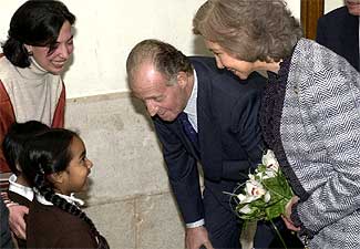 Los Reyes dialogan con dos niños en su visita al colegio del barrio de Maravillas.