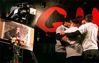 Un grupo de periodistas de Tele 5 abrazan a un hermano del cámara José Couso, cuya foto aparece a la izquierda, tras la manifestación en Madrid.