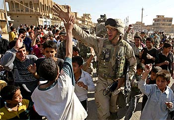 Un  marine  es saludado ayer por un grupo de niños mientras patrulla por el barrio bagdadí de Sadam City.