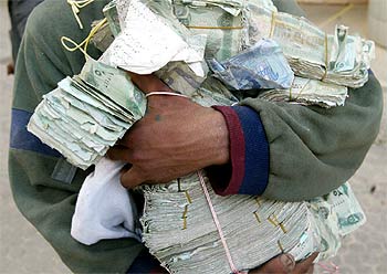 Un iraquí muestra los fajos de billetes que ha robado de un banco asaltado en Bagdad, el jueves.