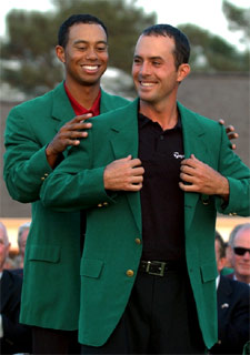 Tiger Woods, campeón el año pasado, le coloca la chaqueta verde a Mike Weir.
