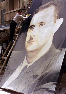 Un empleado saca brillo a un cartel del presidente El Asad, ayer en Damasco.