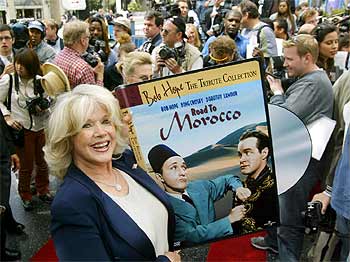 Connie Stevens muestra un cartel de promoción de la celebración de los cien años de Bob Hope.