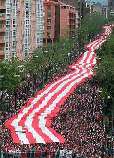 La enorme bandera bufanda en una de las calles del trayecto entre Neptuno y el Manzanares.rnrnUn aficionado, en la pradera de San Isidro.