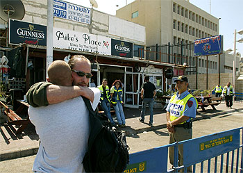 El dueño de la cafetería de Tel Aviv víctima del atentado (con gafas) se abraza a un amigo tras el atentado. rnrn AP