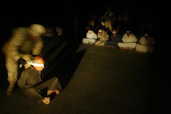 Un soldado de la 4ª División de Infantería estadounidense venda los ojos a un detenido, tras una incursión ayer en Tikrit.rnrn  ASSOCIATED PRESS