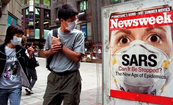 Transeúntes en Hong Kong con mascarillas para protegerse contra la neumonía atípica miran un anuncio de la portada de la revista  Newsweek  dedicada a la epidemia . 