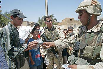 Soldados estadounidenses le compran un periódico a un joven en Bagdad.