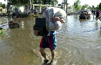 Un hombre carga con sus pertenencias entre las aguas desbordadas del río Salado, en la ciudad argentina de Santa Fe.