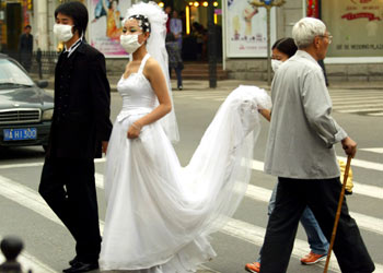 Dos novios y una dama de honor con mascarilla se cruzan con un anciano en Wuhan (provincia de Hubei, China).