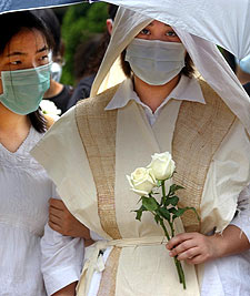 La viuda de un enfermero muerto por la neumonía en Hong Kong, en  el entierro del marido.rnrn AP