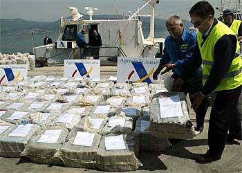 Agentes de policía colocan los sacos con cocaína que se aprehendieron a bordo del torpedero  Cork. 